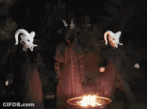 A Group Of Devils Standing Around A Fire At Night GIF