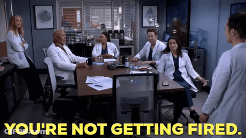 A Group Of Doctors Are Sitting Around A Table With The Words You 'Re Not Getting Fired GIF