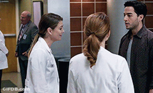 A Group Of Doctors Are Standing Next To Each Other In A Hallway . GIF