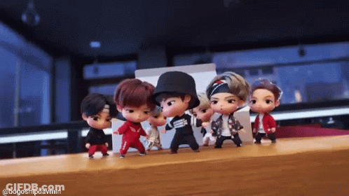 A Group Of Dolls Are Dancing Together On A Table . GIF