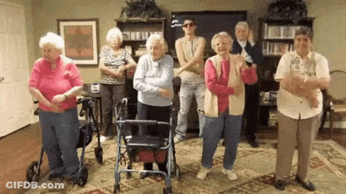 A Group Of Elderly People Are Dancing In A Living Room . GIF