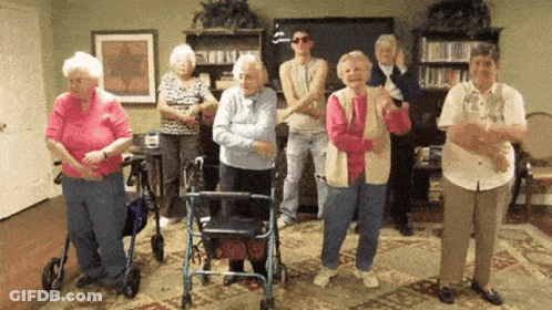 A Group Of Elderly People Are Standing In A Room Dancing GIF