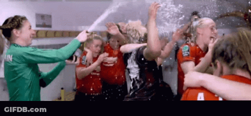 A Group Of Female Soccer Players Are Celebrating In A Locker Room And One Of Their Shirts Has The Letter A On It GIF