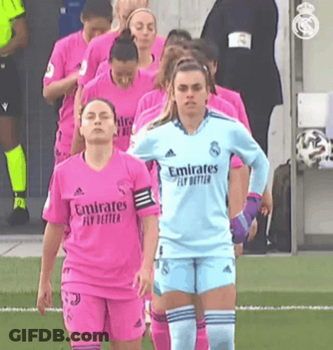 A Group Of Female Soccer Players Wearing Pink Jerseys Are Walking On A Field . GIF