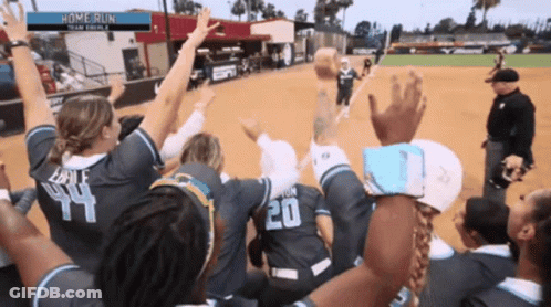 A Group Of Female Softball Players Celebrate A Home Run With Their Arms In The Air GIF