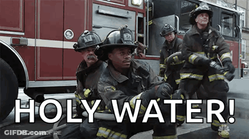 A Group Of Firefighters Are Kneeling In Front Of A Fire Truck And Holding Hoses . GIF
