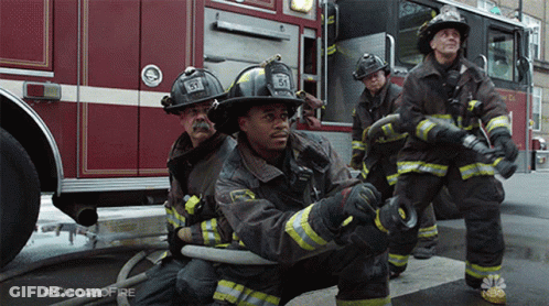 A Group Of Firefighters Are Kneeling In Front Of A Fire Truck With #Chicagofire Written On The Bottom GIF