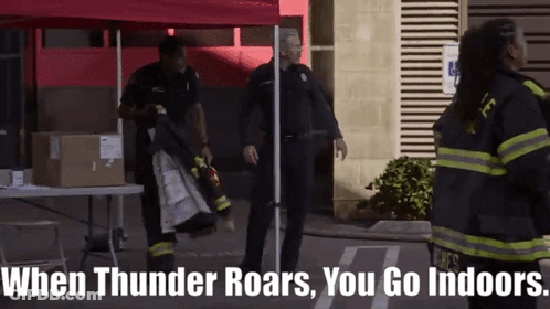 A Group Of Firefighters Are Standing In Front Of A Red Tent With The Words When Thunder Roars You Go Indoors GIF
