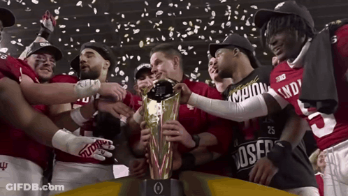 A Group Of Football Players Are Holding A Trophy And One Of Them Has The Number 25 On His Shirt GIF