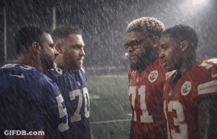 A Group Of Football Players Are Huddled Together In The Rain And One Of Them Has The Number 13 On His Jersey GIF