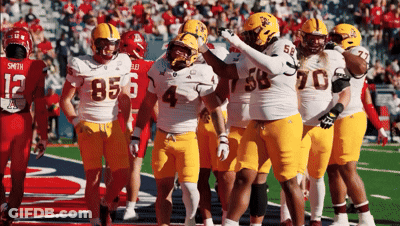 A Group Of Football Players Are Huddled Together With One Wearing The Number 4 GIF