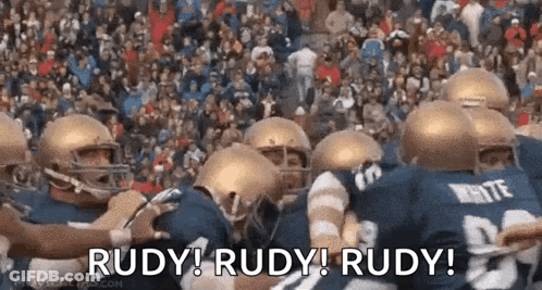 A Group Of Football Players Are Huddled Together With The Words Rudy ! Rudy ! Rudy ! Written On The Bottom GIF