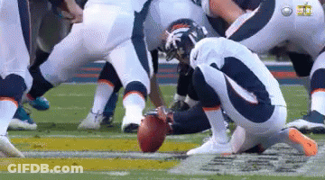A Group Of Football Players Are Kneeling Down On The Field Holding A Football . GIF