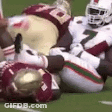 A Group Of Football Players Are Laying On The Ground . GIF