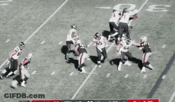A Group Of Football Players Are On A Field Playing A Game Of Football . GIF