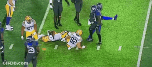 A Group Of Football Players Are Playing A Game On A Field . GIF
