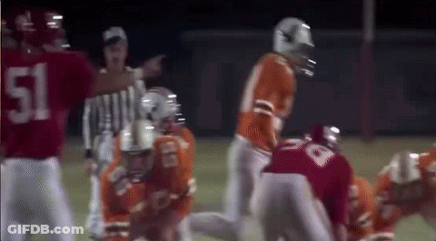 A Group Of Football Players Are Playing A Game On A Field With A Referee . GIF