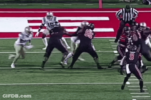 A Group Of Football Players Are Playing A Game On A Field With A Referee . GIF