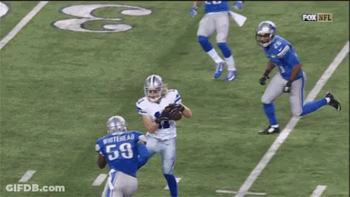 A Group Of Football Players Are Playing A Game On A Field With A Referee In The Background . GIF