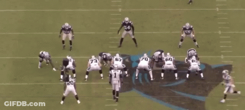 A Group Of Football Players Are Playing A Game On A Field With A Referee In The Middle . GIF