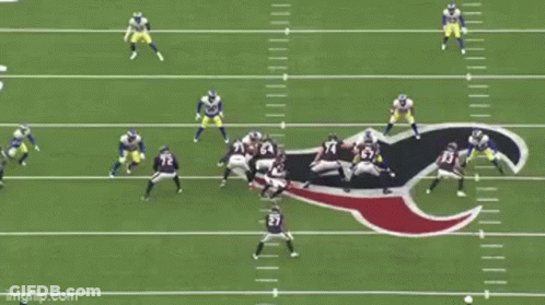 A Group Of Football Players Are Playing A Game On A Field With A Referee . GIF