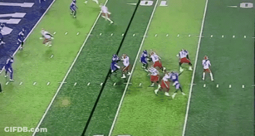 A Group Of Football Players Are Playing A Game On A Green Field . GIF