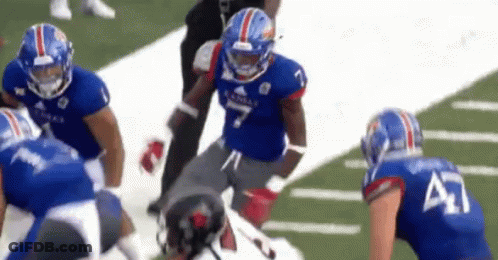 A Group Of Football Players Are Playing A Game On The Field . GIF