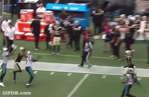 A Group Of Football Players Are Playing On A Field With Gatorade Coolers In The Background . GIF