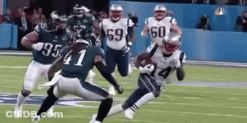A Group Of Football Players Are Running On A Field . GIF