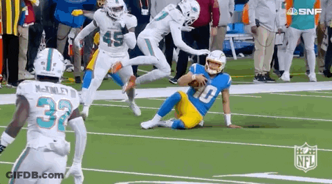 A Group Of Football Players Are Running On A Field . GIF