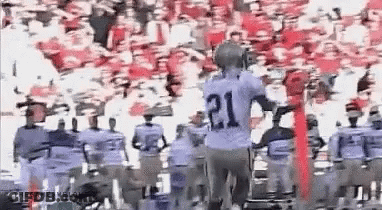 A Group Of Football Players Are Standing In Front Of A Crowd . GIF
