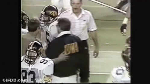 A Group Of Football Players Are Standing Next To Each Other On A Field With A Referee . GIF