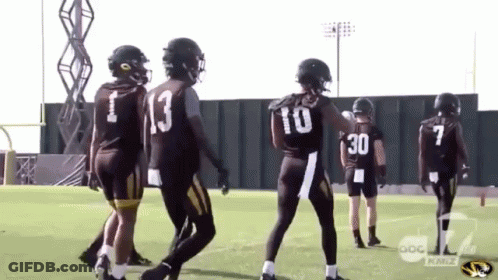A Group Of Football Players Are Standing On A Field And One Has The Number 30 On His Back . GIF