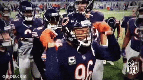 A Group Of Football Players Are Standing On A Field And One Of Them Is Wearing A Helmet With The Letter C On It . GIF