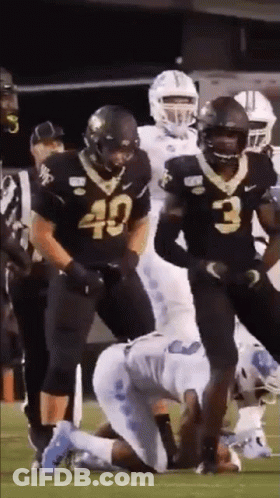 A Group Of Football Players Are Standing On A Field . GIF