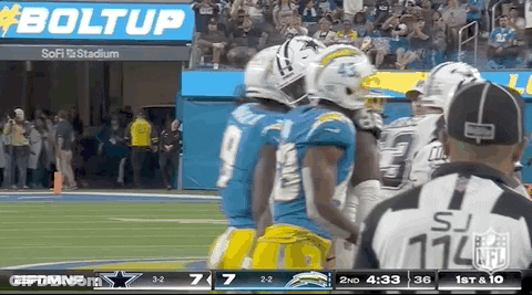 A Group Of Football Players Are Standing On A Field Next To A Referee . GIF