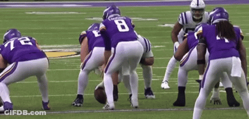 A Group Of Football Players Are Standing On A Field . GIF