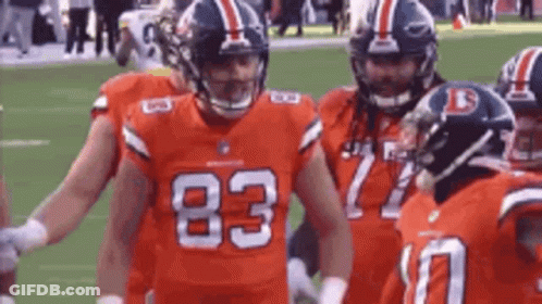 A Group Of Football Players Are Standing On A Field With Their Arms Around Each Other . GIF