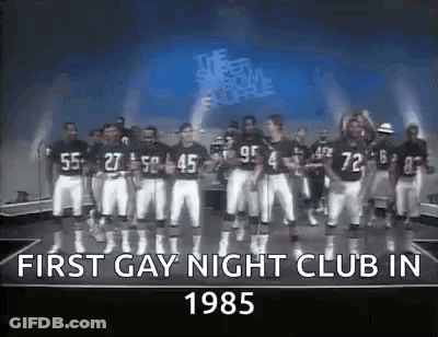 A Group Of Football Players Are Standing On A Stage In Front Of A Sign That Says First Gay Night Club In 1985 . GIF