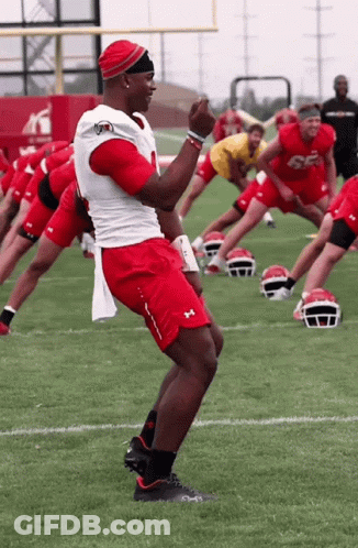A Group Of Football Players Are Stretching On The Field And One Of Them Has The Number 56 On His Jersey GIF