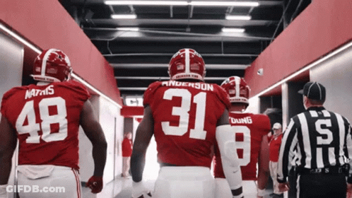A Group Of Football Players Are Walking Down A Hallway And One Of Them Has The Number 31 On His Jersey GIF