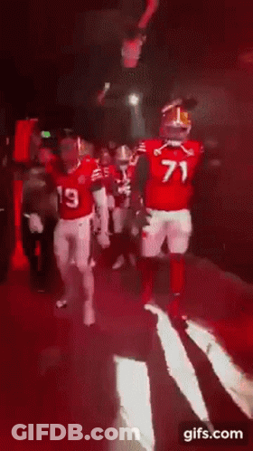 A Group Of Football Players Are Walking Down A Red Carpet With The Number 71 On Their Jersey GIF