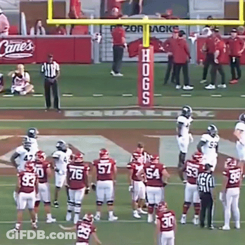 A Group Of Football Players On A Field With A Sign That Says Hogs On It GIF