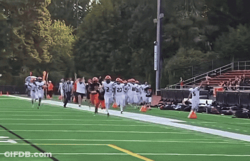 A Group Of Football Players Running On A Field With One Wearing The Number 21 GIF