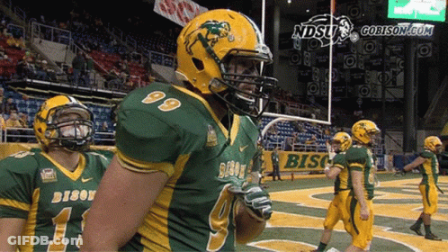 A Group Of Football Players Wearing Green And Yellow Uniforms With The Word Bison On Them GIF