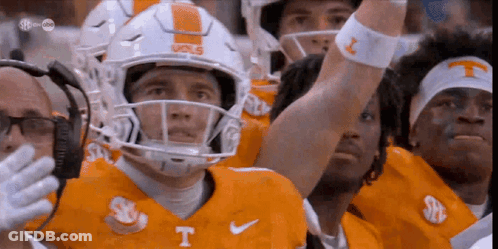 A Group Of Football Players Wearing Orange Uniforms With The Letter T On Them GIF