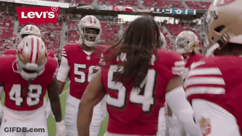 A Group Of Football Players Wearing Red Jerseys With The Number 54 On The Back GIF