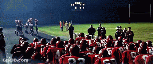 A Group Of Football Players Wearing Red Uniforms With The Number 22 On The Back Stand In Front Of A Scoreboard GIF