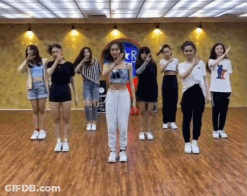 A Group Of Girls Are Dancing In A Room With A Sign That Says R. GIF