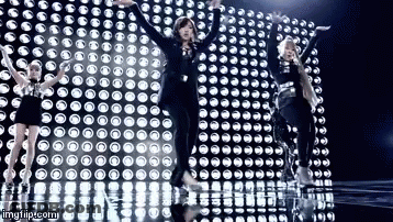 A Group Of Girls Are Dancing In Front Of A Wall Of Lights . GIF